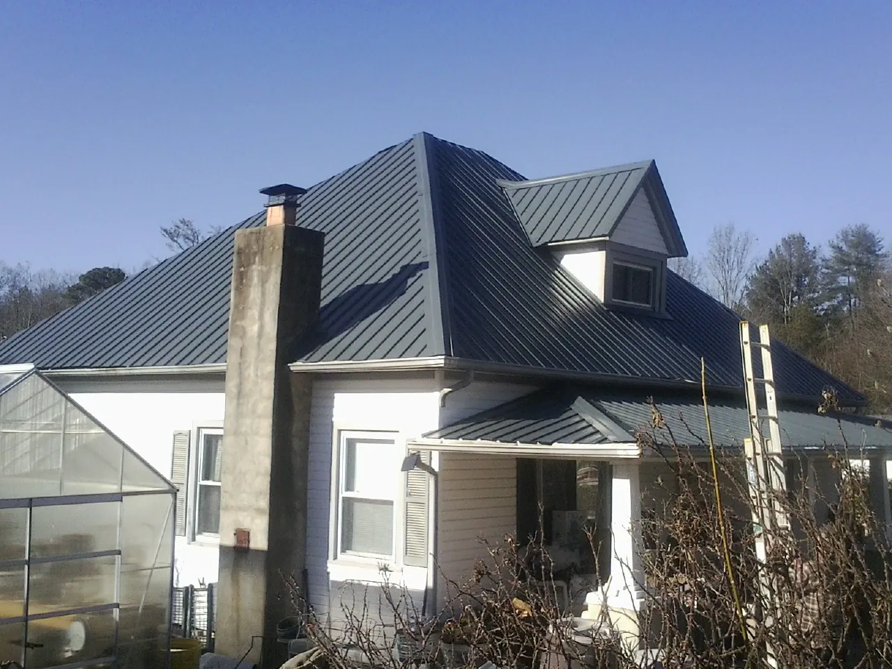 Dark blue standing seam metal roof on a white farmhouse with dormer — Slate & Tile Roof Repair by Roofing Brothers in Slaterville Springs
