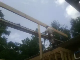 Carpenter setting a ridge beam over a new addition frame — Ice Dam Removal by Roofing Brothers in Slaterville Springs