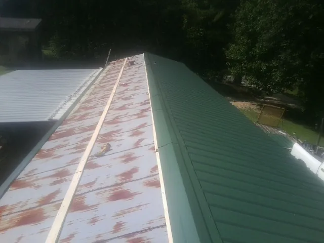 Old rusted panels beside newly installed green metal roofing — Wind Damage Roof Repair by Roofing Brothers in Slaterville Springs