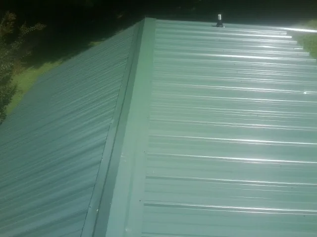 New green metal panels meeting at the ridge of a roof — Flat Roof Repair work by our crew in Slaterville Springs