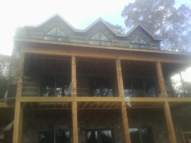 Dormers and porch framing on a large log home under construction — Roof Coating work by our crew in Slaterville Springs