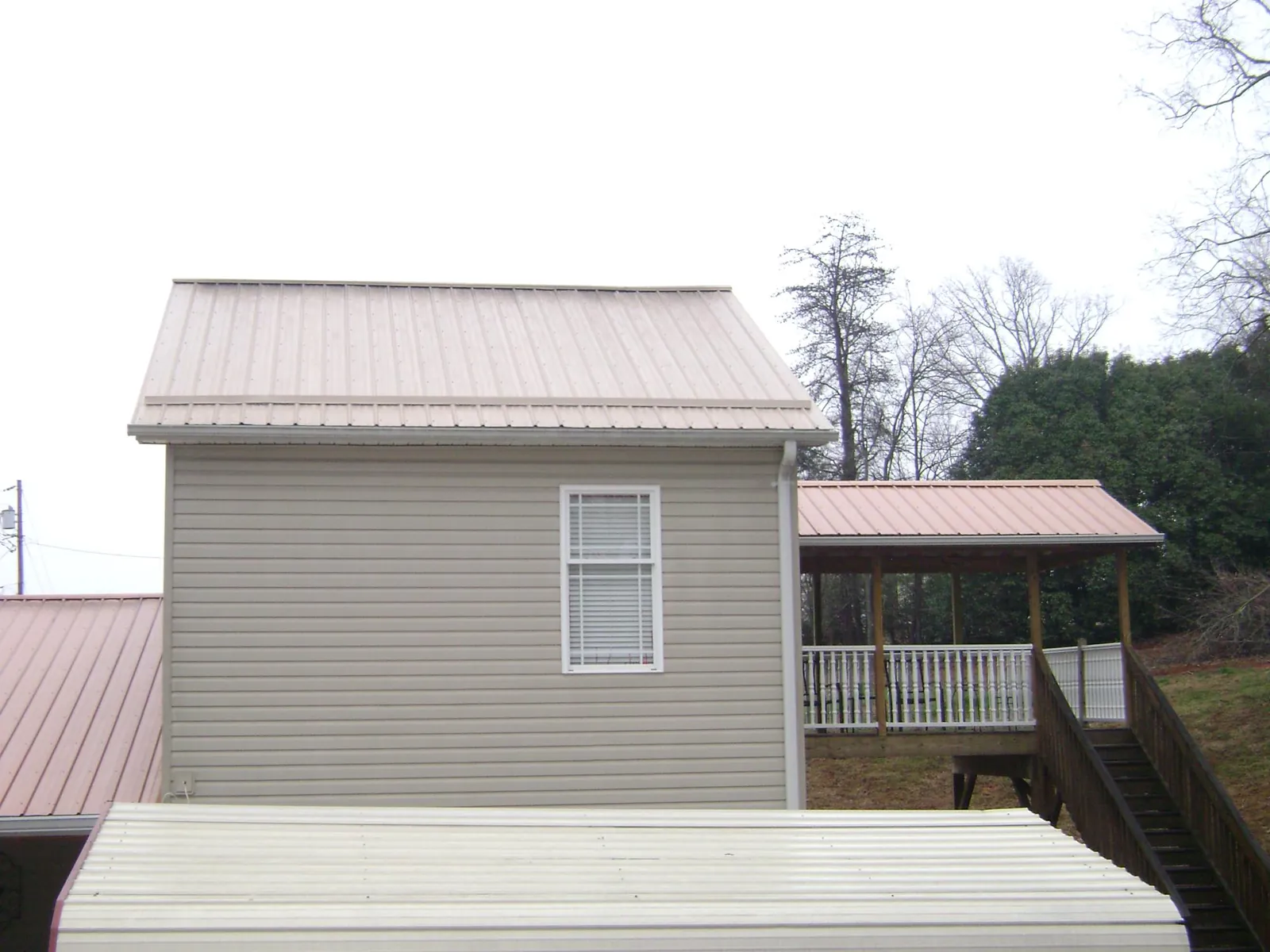 Tan metal roofs on a two story addition and attached porch, from a Roof Replacement job in Slaterville Springs