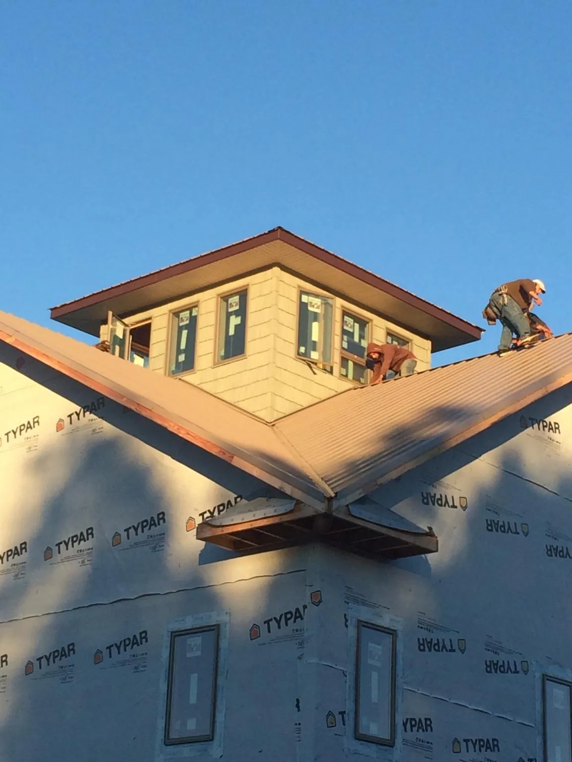 Roofers working around a rooftop cupola on a new metal roof at sunset — Roof Waterproofing in Slaterville Springs by Roofing Brothers